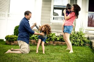 A family plays outside, enjoying sunny weather while saving on HVAC costs with a membership in Calgary.