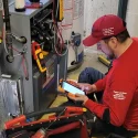 AIC technician performing high-efficiency gas furnace repair service in a Calgary home