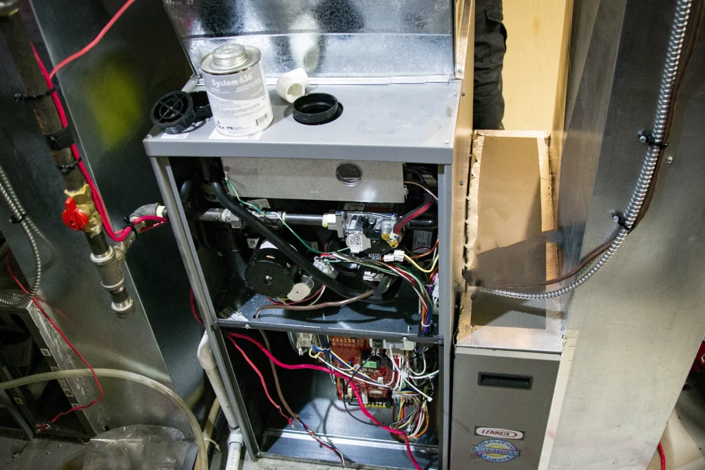 Technicians positioning a new furnace during a Calgary double furnace replacement